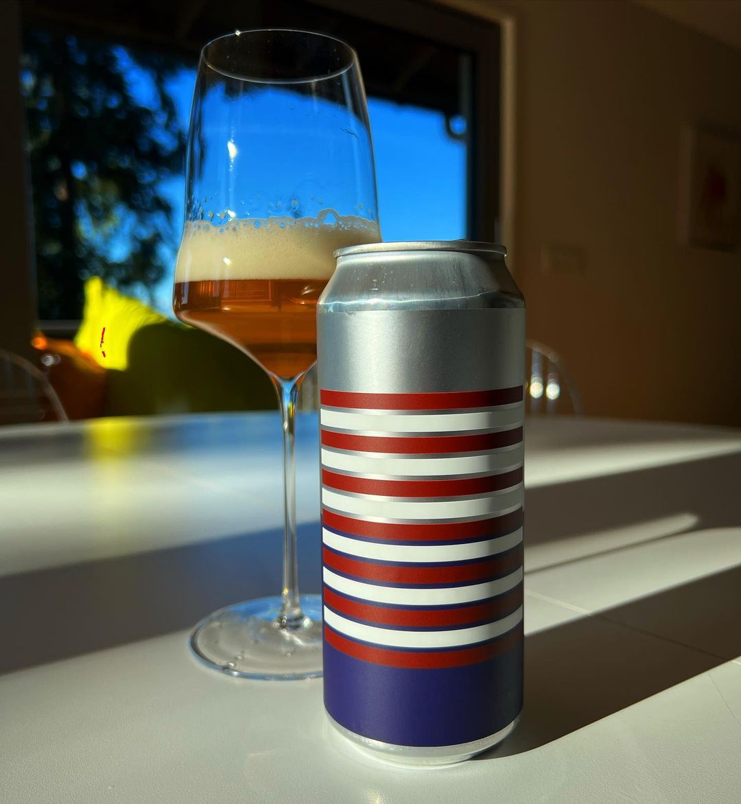 Image of stateside in a stemmed beer glass with can in the foreground